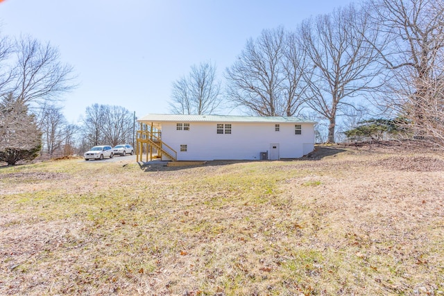 back of house with metal roof and a lawn