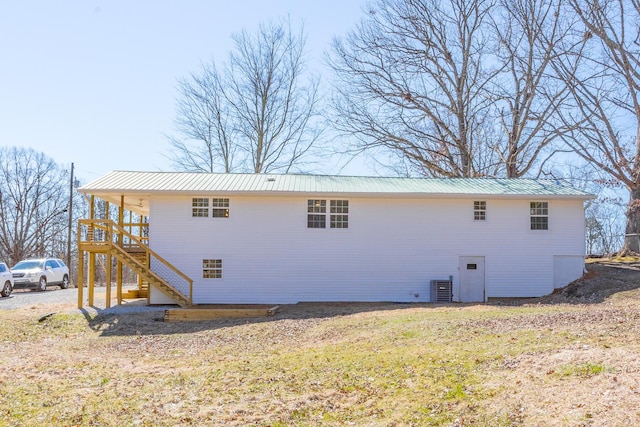 rear view of property with cooling unit, metal roof, and stairs