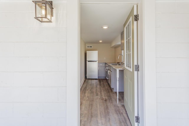 hall with dark wood-style floors, a sink, concrete block wall, and recessed lighting