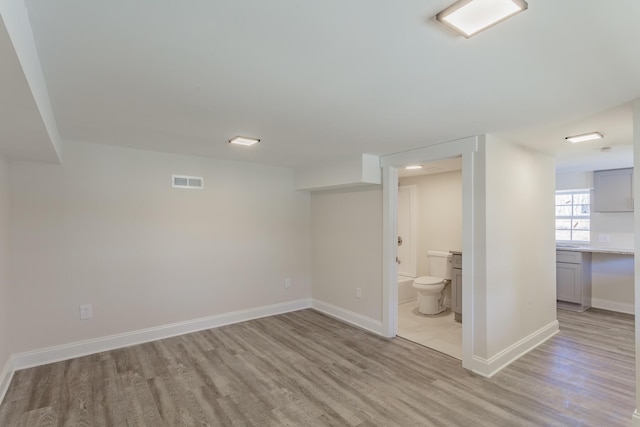 basement featuring light wood-style floors, visible vents, and baseboards