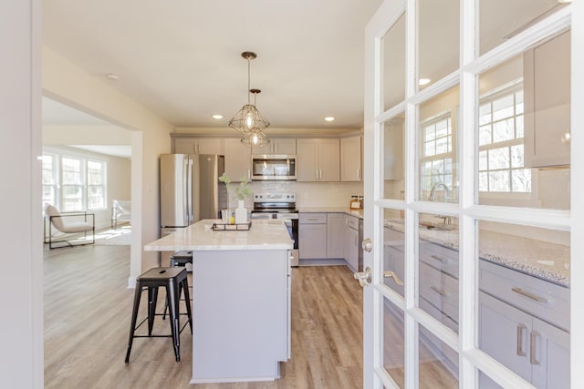 kitchen featuring a center island, stainless steel appliances, tasteful backsplash, light wood-style floors, and a kitchen breakfast bar