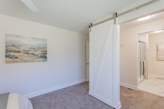 bedroom featuring a barn door, visible vents, baseboards, carpet, and ensuite bath