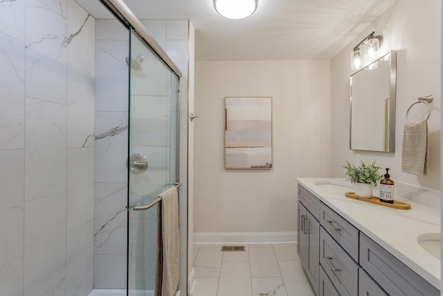 full bathroom with marble finish floor, double vanity, a stall shower, a sink, and baseboards