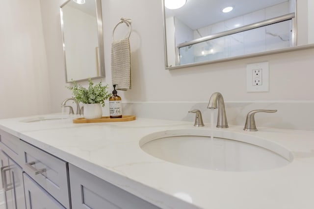 full bath with a shower with door, a sink, and double vanity