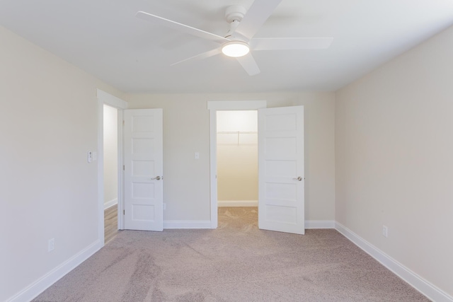 unfurnished bedroom with a closet, a spacious closet, baseboards, and carpet flooring