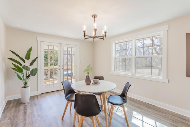 dining space with baseboards, a chandelier, wood finished floors, and french doors