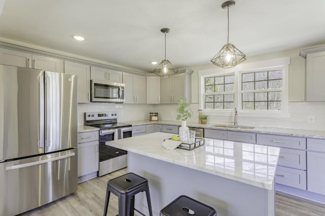 kitchen featuring light wood-style flooring, stainless steel appliances, a breakfast bar, a sink, and backsplash