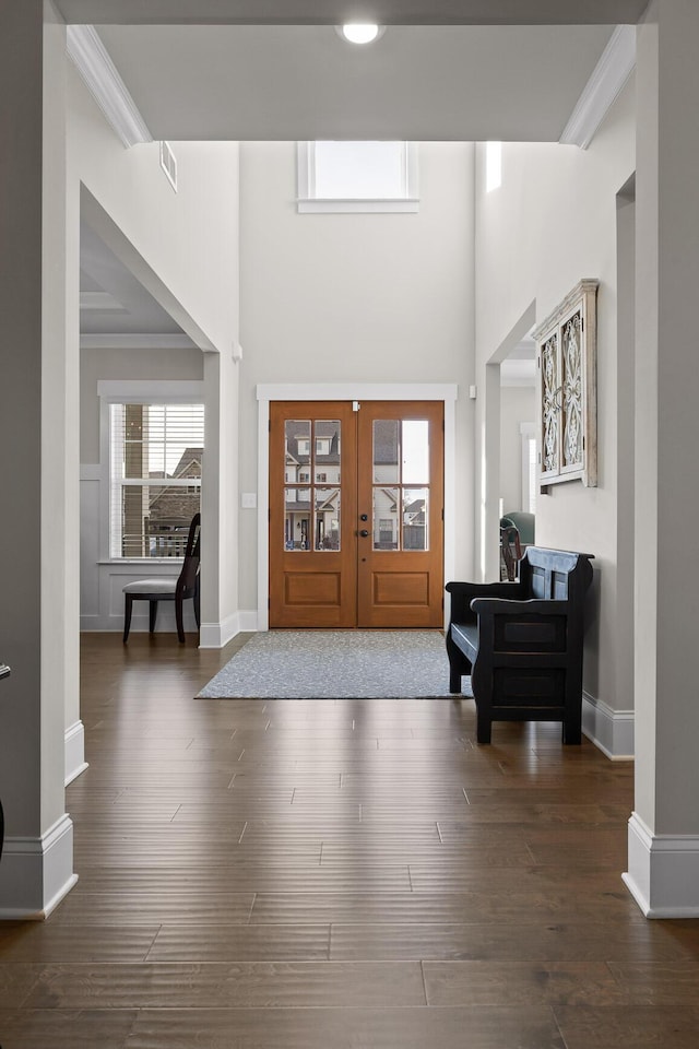 entrance foyer with ornamental molding, french doors, dark wood-type flooring, and a high ceiling