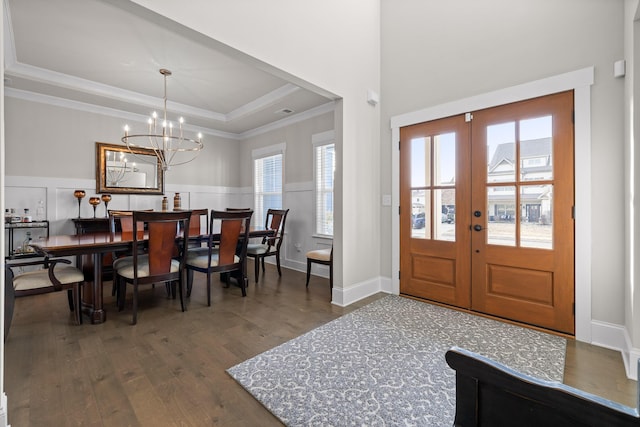 entrance foyer featuring a wainscoted wall, crown molding, a raised ceiling, dark wood-style flooring, and french doors