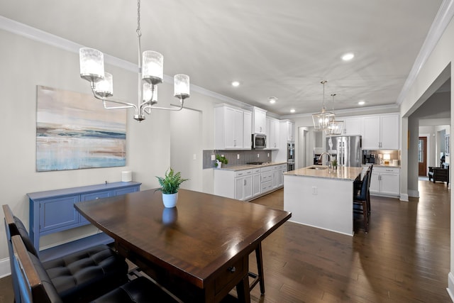 dining space with ornamental molding, a chandelier, sink, and dark hardwood / wood-style floors