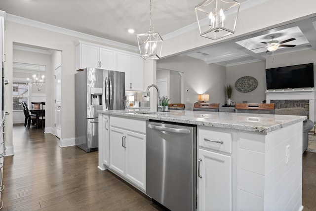 kitchen with appliances with stainless steel finishes, white cabinets, decorative light fixtures, an island with sink, and light stone counters