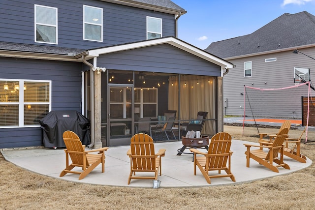 rear view of property featuring a fire pit, a patio area, and a sunroom