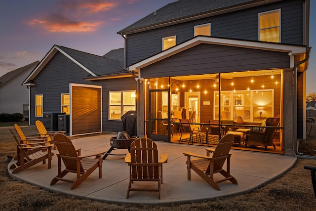 back house at dusk featuring a fire pit and a patio