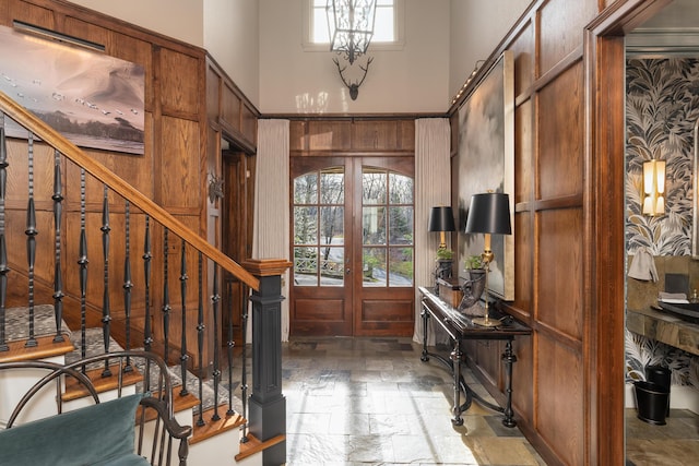 foyer featuring french doors, stairway, a high ceiling, and stone tile flooring