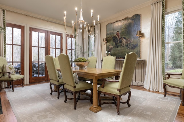 dining room with crown molding, french doors, light wood-style floors, and a notable chandelier