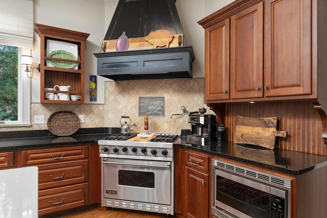 kitchen with premium range hood, decorative backsplash, stainless steel appliances, and dark stone countertops