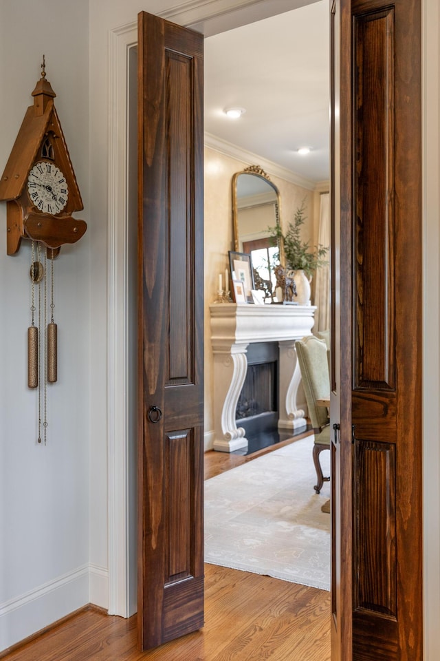 hallway featuring light wood-style floors, baseboards, and ornamental molding