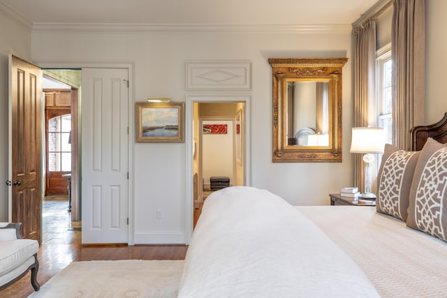 bedroom featuring baseboards, multiple windows, light wood-style flooring, and crown molding