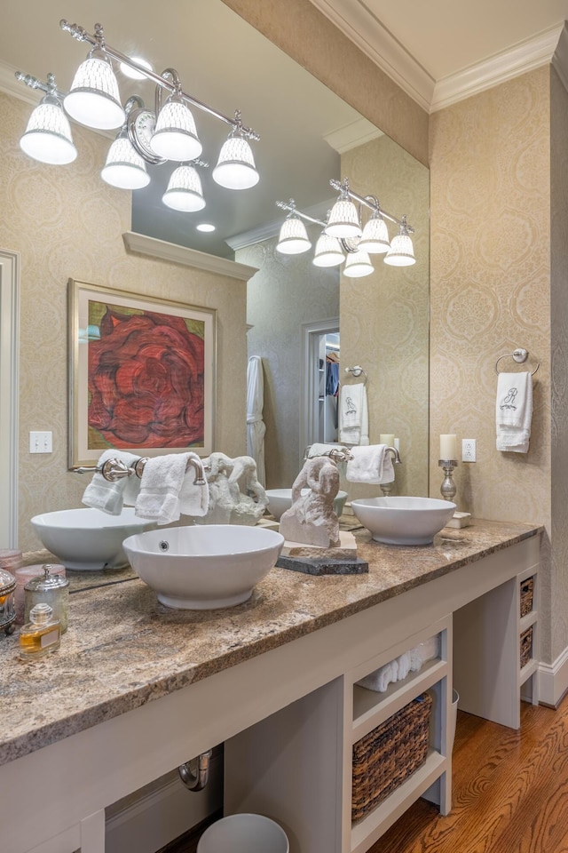 bathroom with crown molding, a sink, and wallpapered walls