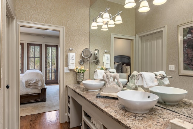 bathroom with wood finished floors, a sink, ensuite bath, and wallpapered walls