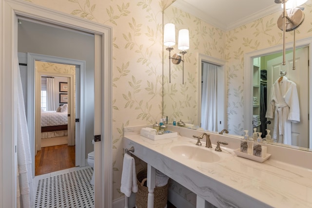 ensuite bathroom with connected bathroom, toilet, a sink, wallpapered walls, and crown molding