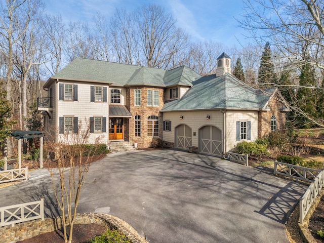 view of front of property featuring aphalt driveway, stone siding, a chimney, and an attached garage