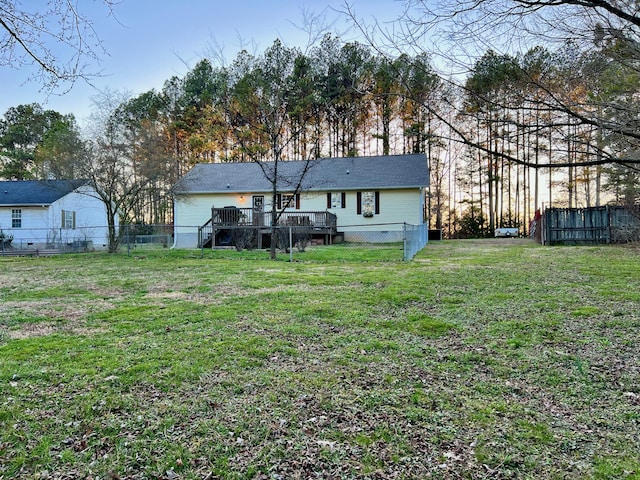 back of house with a lawn, a wooden deck, and fence