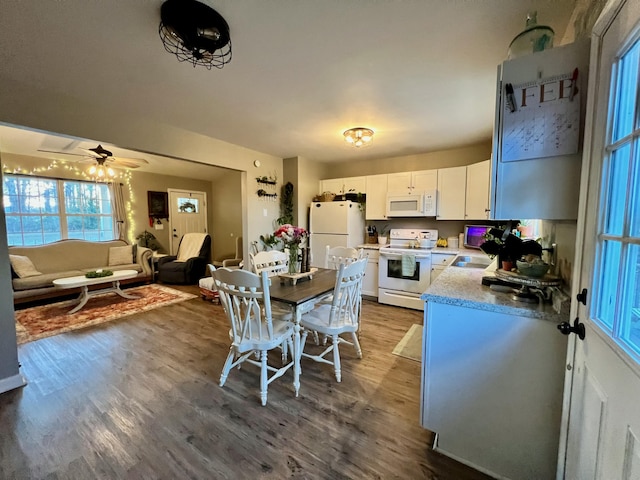 kitchen featuring white appliances, open floor plan, wood finished floors, light countertops, and white cabinetry