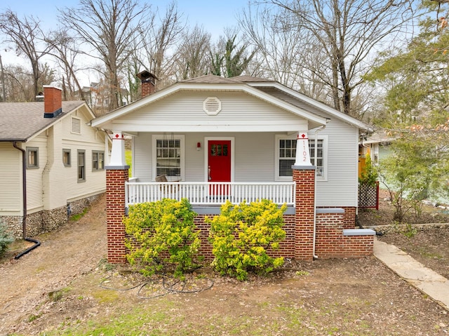 bungalow-style home featuring covered porch and a chimney