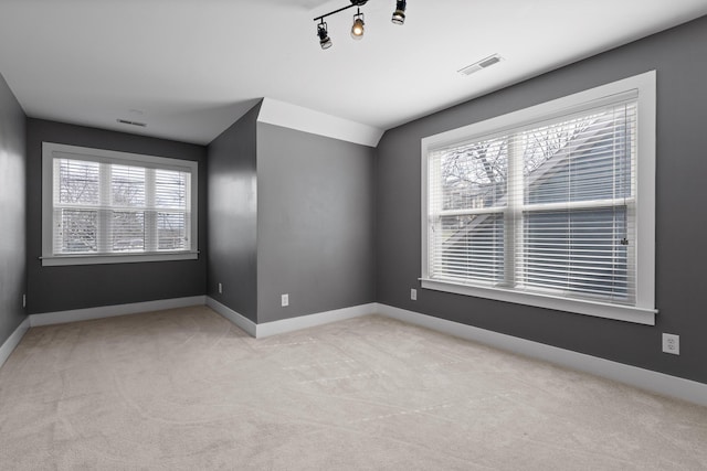 unfurnished room with plenty of natural light, visible vents, baseboards, and light colored carpet