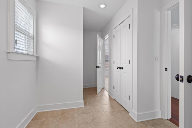 corridor featuring light tile patterned floors and baseboards