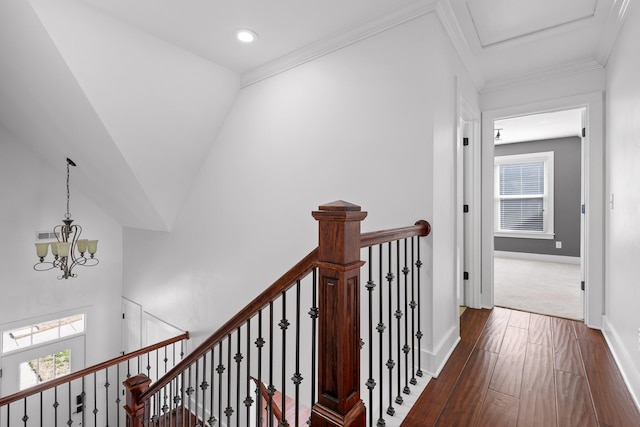 corridor with crown molding, an upstairs landing, baseboards, dark wood finished floors, and an inviting chandelier