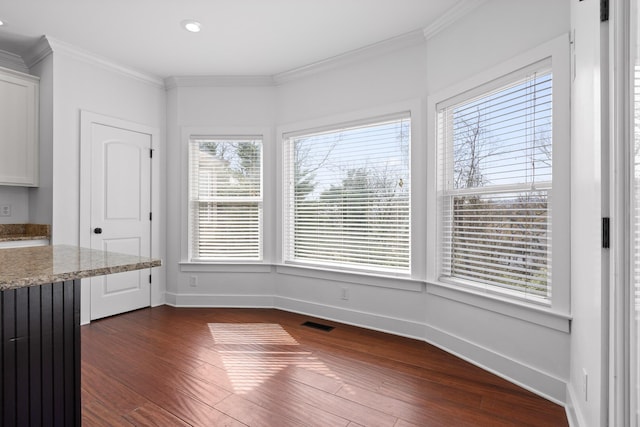 unfurnished dining area featuring baseboards, dark wood-style flooring, visible vents, and crown molding