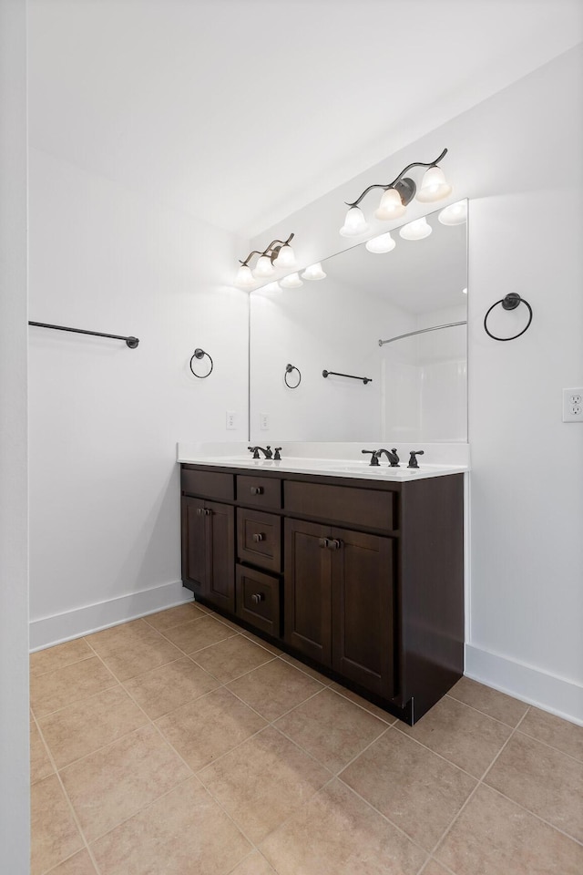 bathroom featuring double vanity, tile patterned flooring, baseboards, and a sink