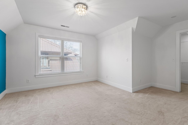 additional living space featuring lofted ceiling, visible vents, baseboards, and light colored carpet