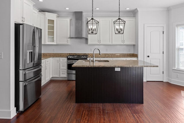 kitchen featuring stainless steel appliances, wall chimney range hood, glass insert cabinets, and a center island with sink