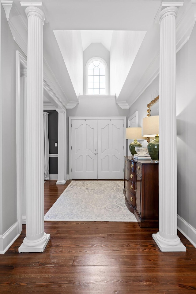entryway with decorative columns, baseboards, vaulted ceiling, and wood-type flooring
