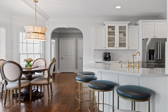kitchen with glass insert cabinets, arched walkways, high quality fridge, light countertops, and white cabinets