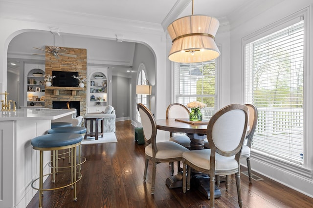 dining area featuring arched walkways, crown molding, and a ceiling fan