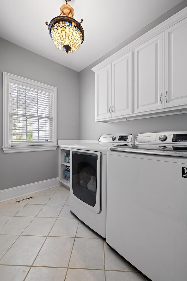 laundry area with baseboards, cabinet space, light tile patterned flooring, and independent washer and dryer