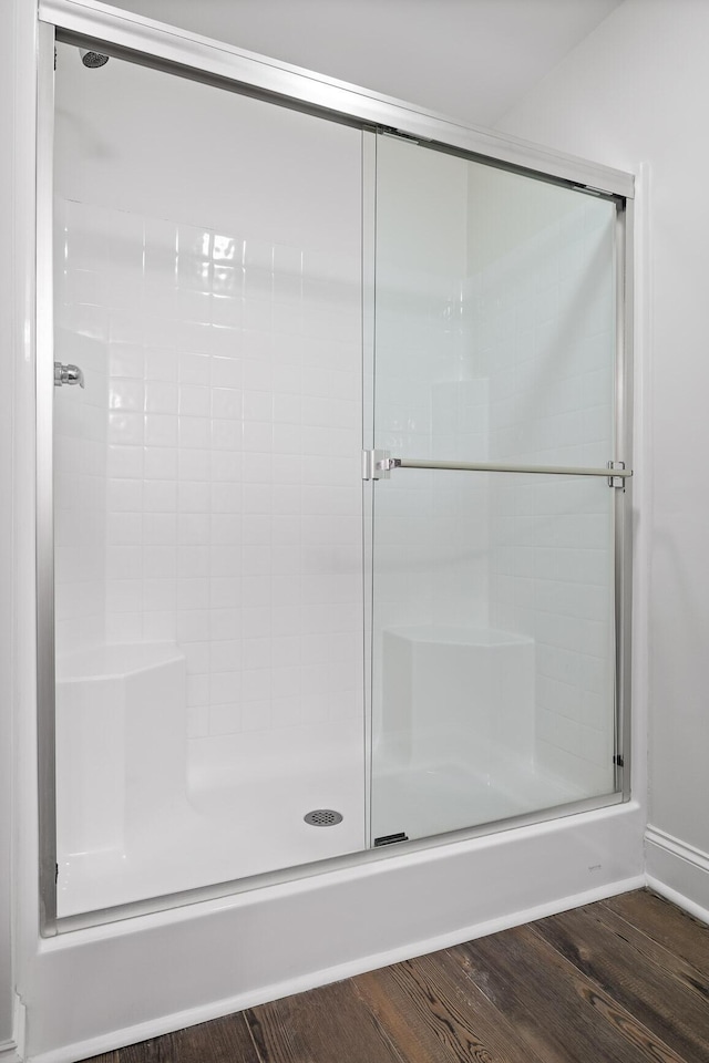 full bath featuring a shower stall, wood finished floors, and baseboards