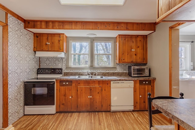 kitchen with brown cabinets, a sink, range with electric cooktop, dishwasher, and under cabinet range hood