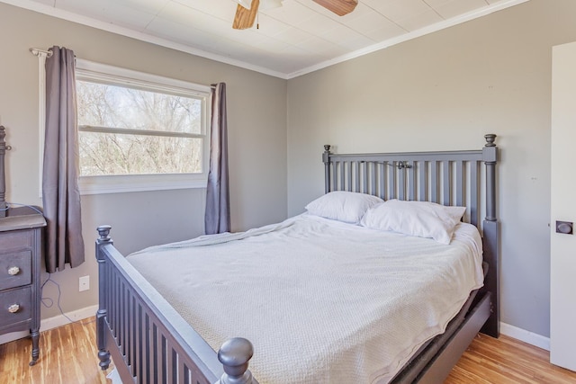 bedroom with ornamental molding, baseboards, light wood finished floors, and a ceiling fan