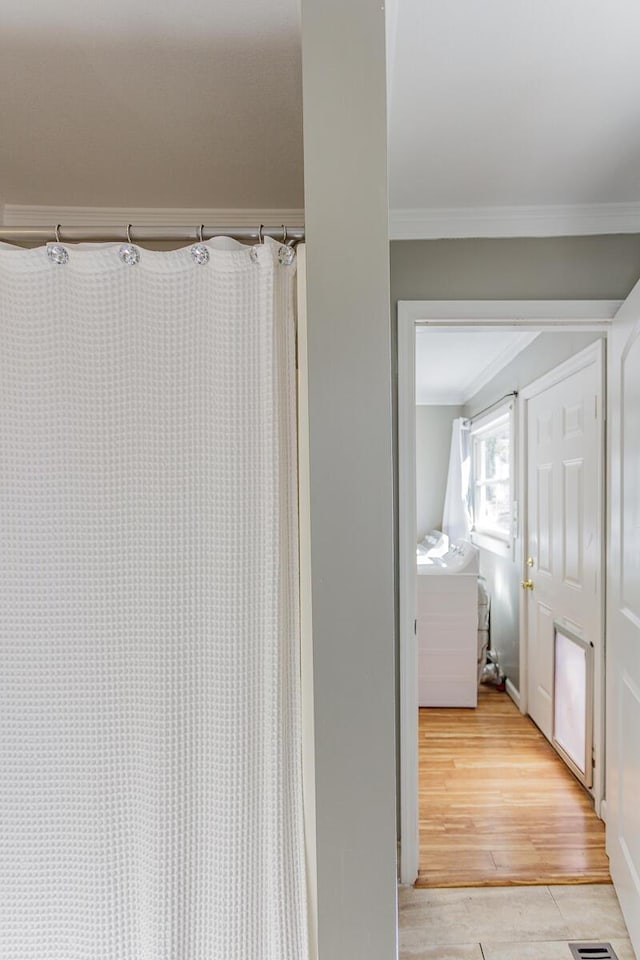 full bathroom with ornamental molding, wood finished floors, and a shower with curtain