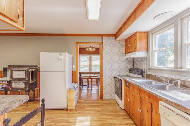 kitchen featuring light wood-style flooring, white appliances, a sink, light countertops, and wallpapered walls