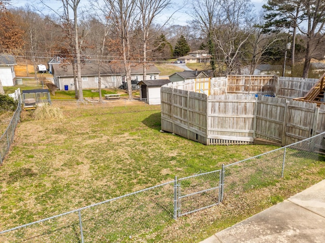 view of yard with a gate, fence, and an outdoor structure