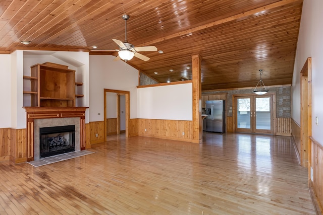 unfurnished living room with wood ceiling, french doors, and wainscoting