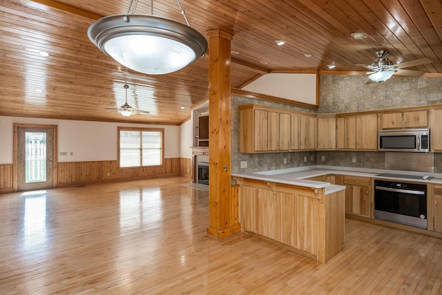 kitchen with a wainscoted wall, stainless steel appliances, light countertops, and pendant lighting