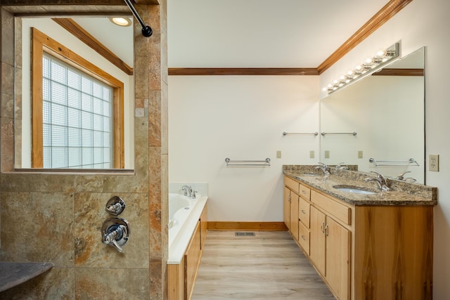 full bathroom featuring ornamental molding, a garden tub, a sink, and double vanity