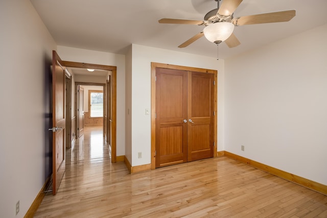 unfurnished bedroom featuring ceiling fan, light wood finished floors, a closet, and baseboards